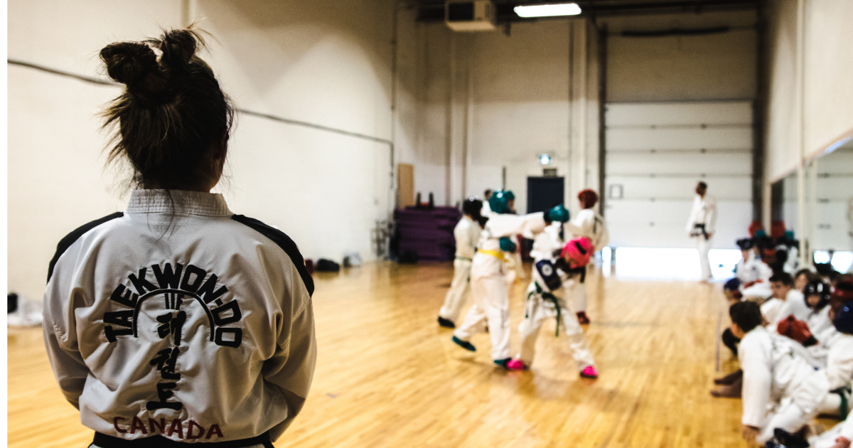 Taekwon-do instructor observing kids sparring at Phoenix Martial Arts summer camp in Canada teaching adolescences Taekwon-do and life lessons.