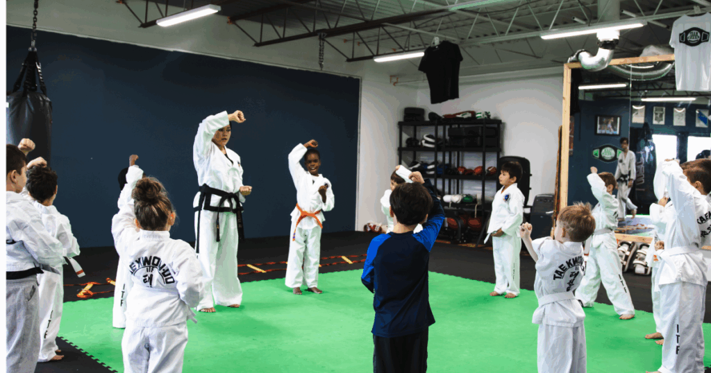 Why More Parents Are Choosing Taekwondo Over Traditional Sports 1 Children practicing Taekwon-do in a structured beginner class with a black belt instructor leading a confidence-building warm-up.