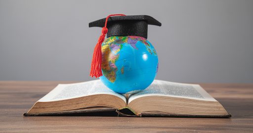 Graduation cap on globe over open book showing learning, goal setting, and school success supported by martial arts