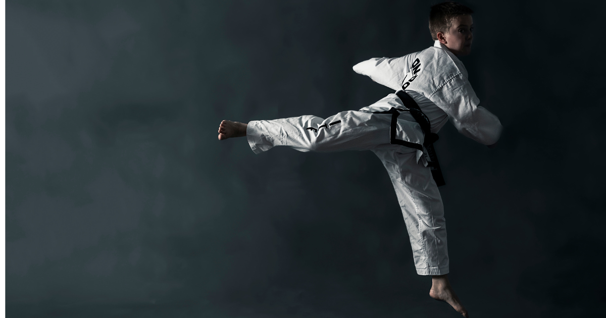 Kid practicing a Taekwon-do side kick to build focus, discipline, and academic success skills for school