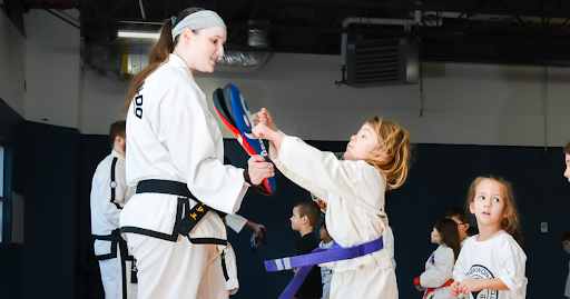 Child practicing a Taekwon-do pad drill with an instructor at Phoenix Martial Arts Club
